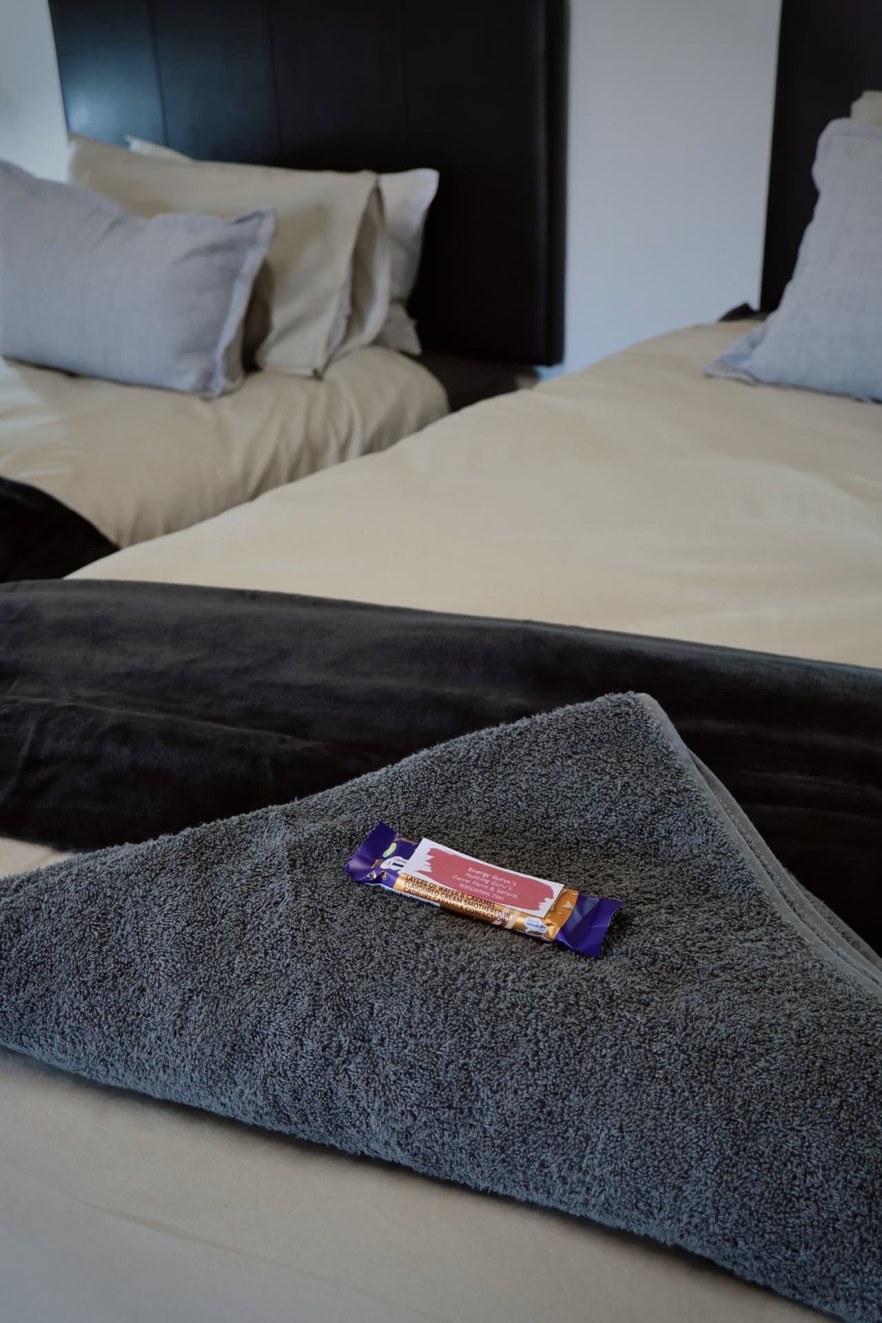 Twin beds with folded towels and welcome chocolate