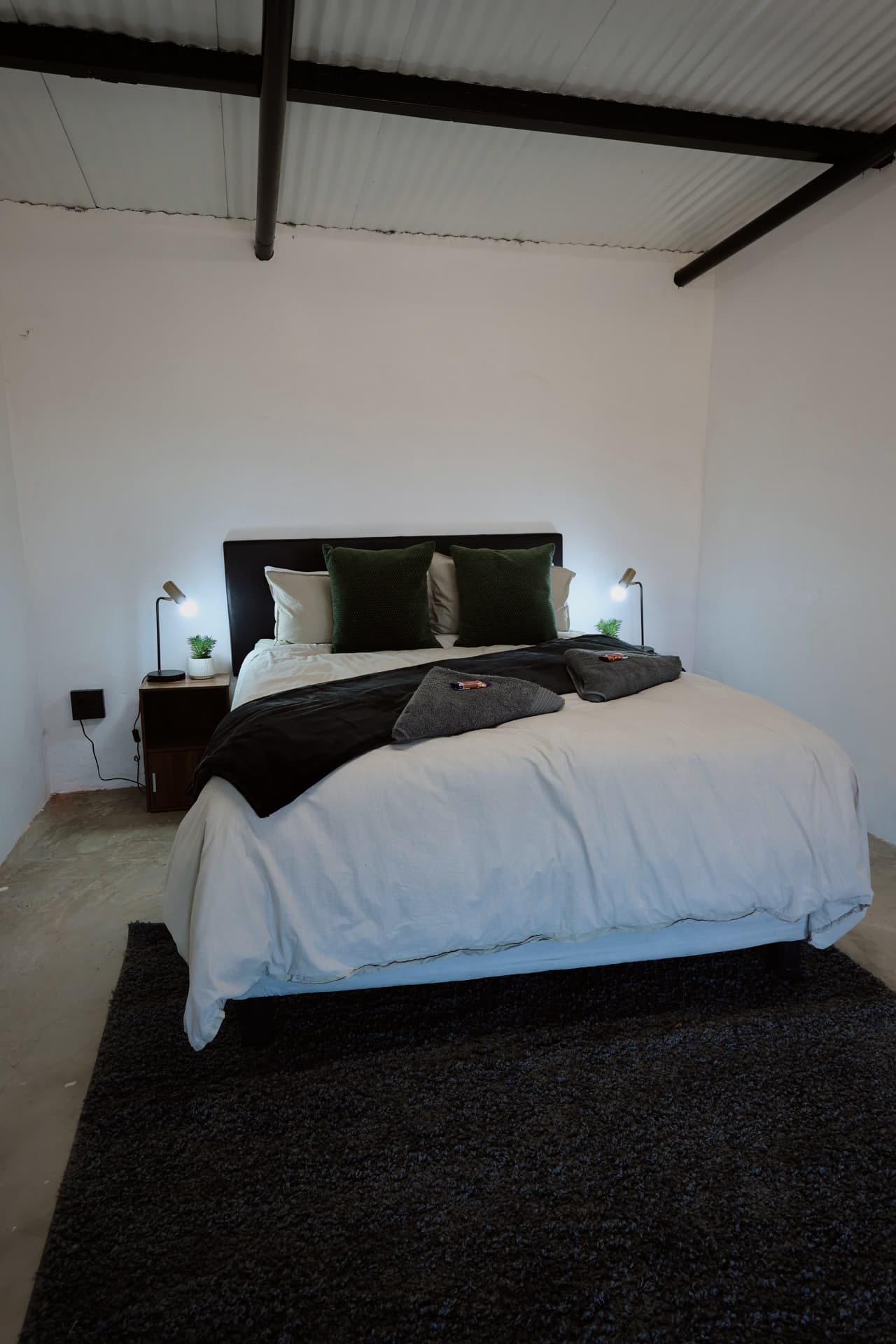 King bed with green scatter cushions and towels