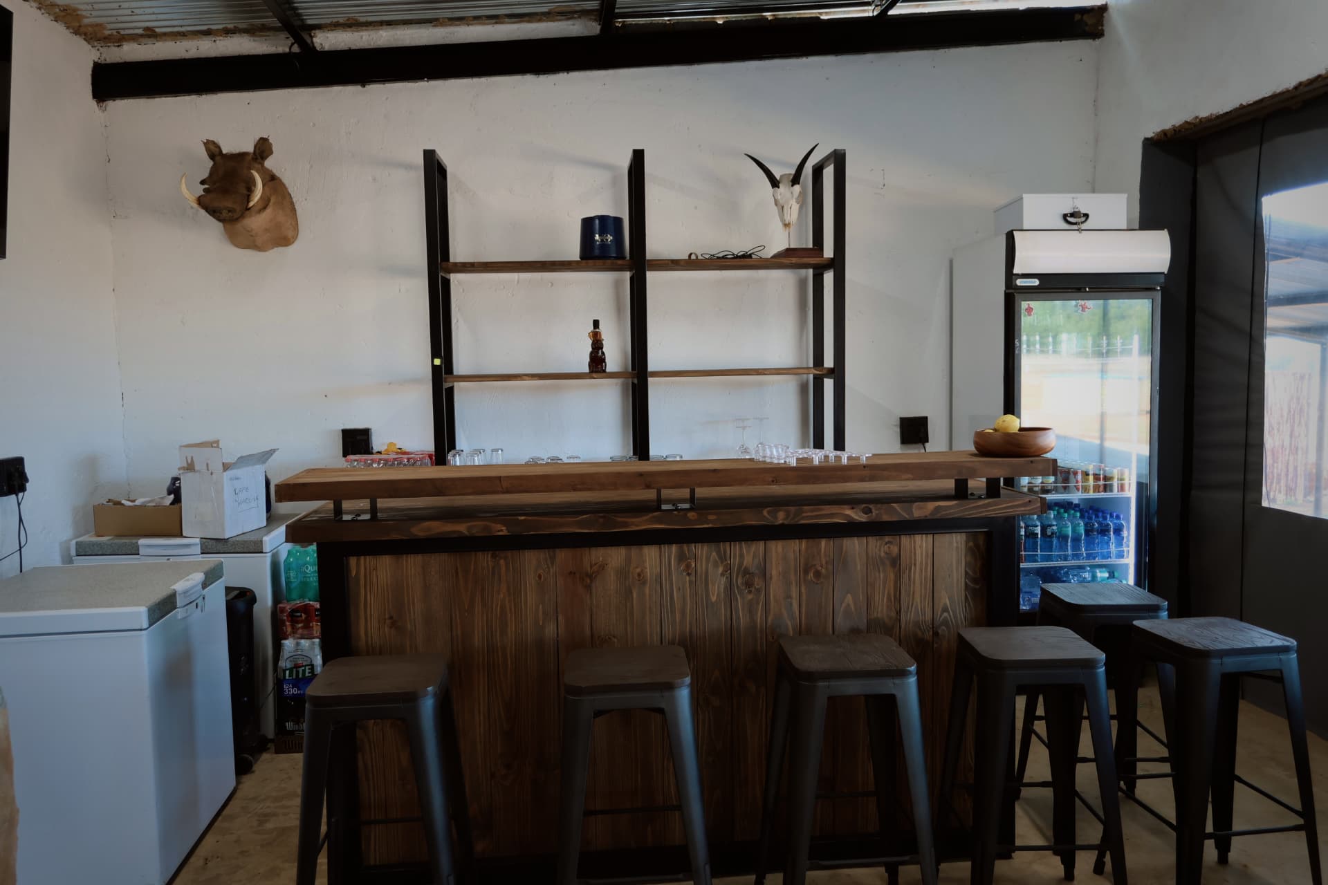 Lodge bar with wooden counter, stools and drinks fridge