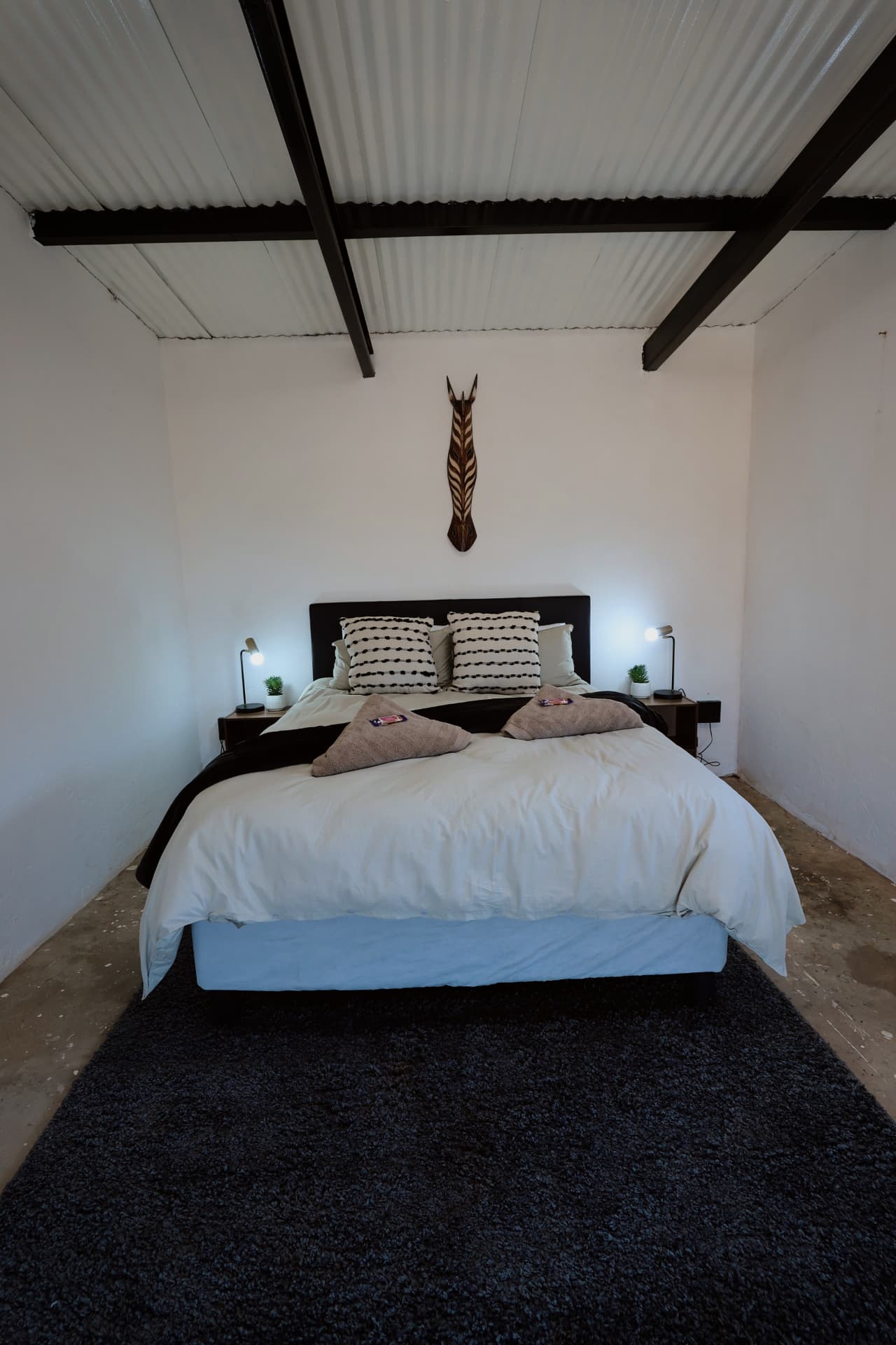 King room with zebra wall art and dark rug
